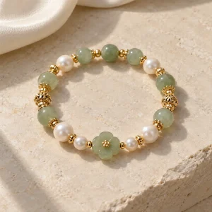 Concept illustration: soft pearl white and pale green bead bracelet with warm gold tone accent, joy inspired. Not an actual product photograph.