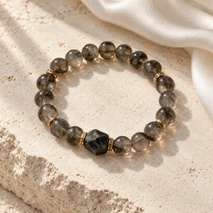 Concept illustration: smoky gray bead bracelet with one dark stone geometric accent, mountain stillness inspired. Not an actual product photograph.