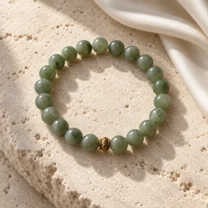 Concept illustration: muted jade green bead bracelet with a tiny antique gold tone accent. Not an actual product photograph.