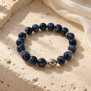 Concept illustration: deep midnight blue bead bracelet with subtle silver tone accent, flowing water inspired. Not an actual product photograph.