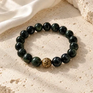 Concept illustration: minimal polished black bead bracelet with a single antique gold tone accent. Not an actual product photograph.