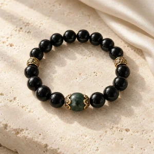 Concept illustration: polished black bead bracelet with three restrained gold tone accents, the Heavens inspired. Not an actual product photograph.