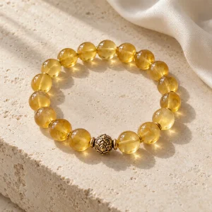 Concept illustration: translucent honey yellow bead bracelet with a small antique gold tone accent. Not an actual product photograph.